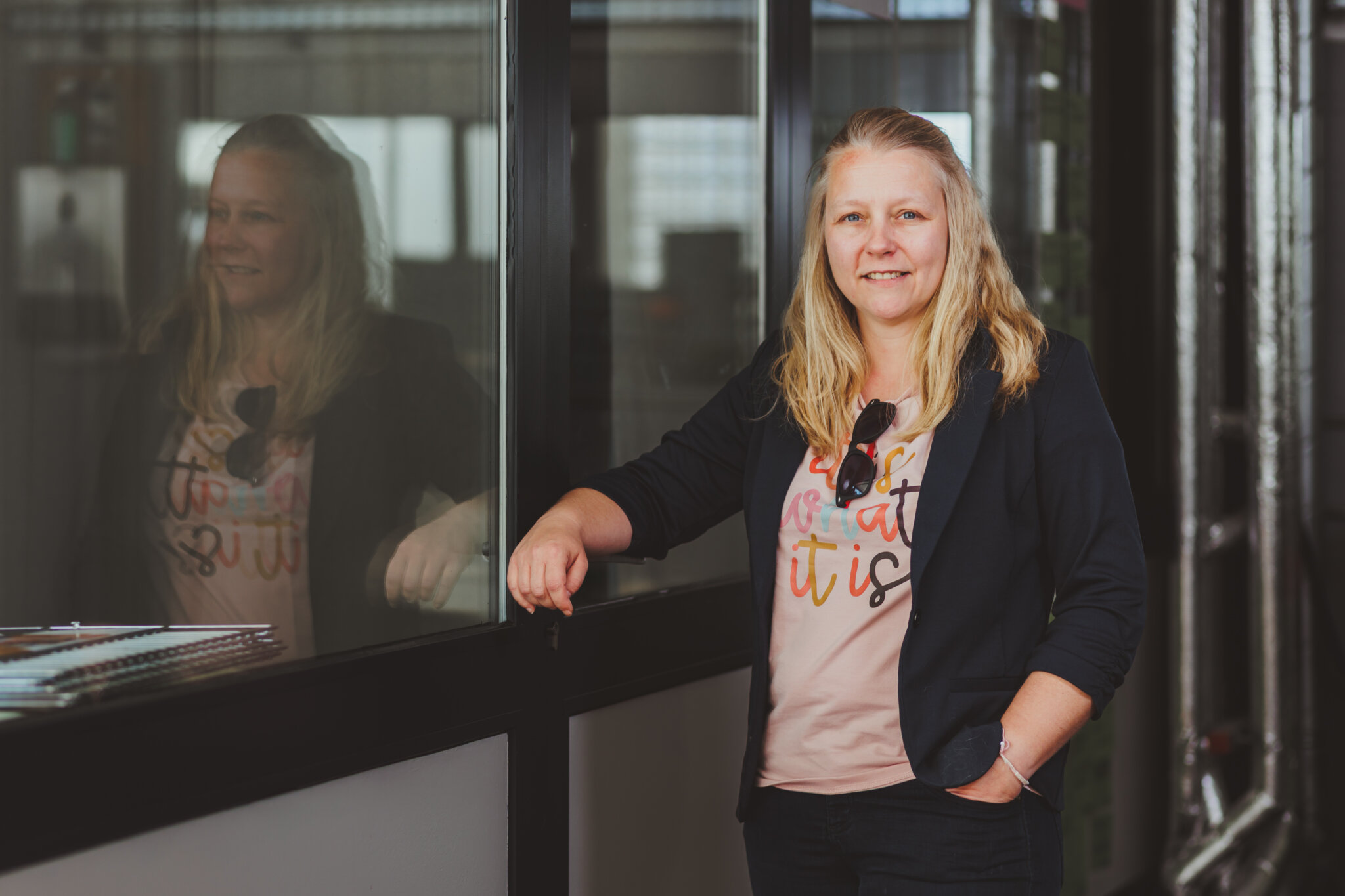 Susann Schlatterer steht an einem Fenster, in dem sich ihr Spiegelbild zeigt